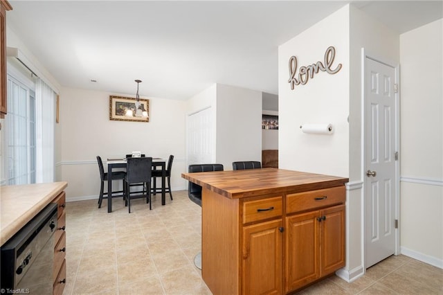 kitchen featuring hanging light fixtures, brown cabinets, dishwasher, baseboards, and butcher block counters