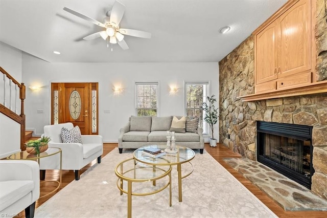 living room with a fireplace, a ceiling fan, stairs, and wood finished floors