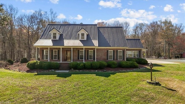 cape cod house featuring a front yard, brick siding, a porch, and metal roof