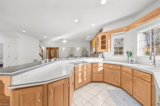 kitchen with black electric cooktop, a peninsula, glass insert cabinets, a sink, and light tile patterned floors
