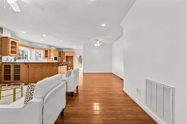 living room with baseboards, visible vents, light wood-style floors, ceiling fan, and recessed lighting
