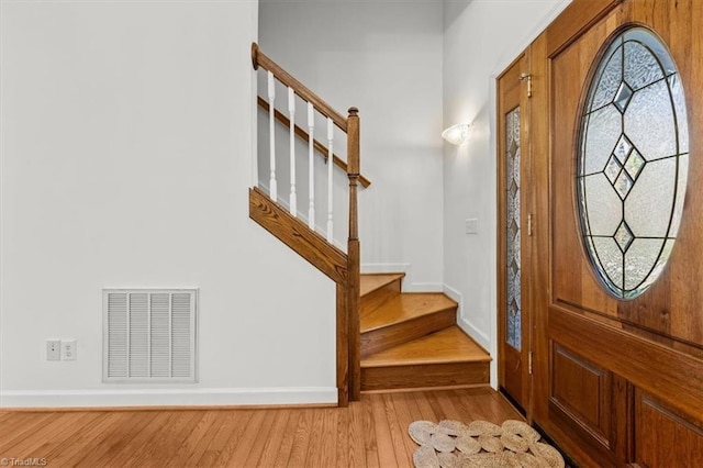 entryway featuring stairs, visible vents, wood finished floors, and baseboards