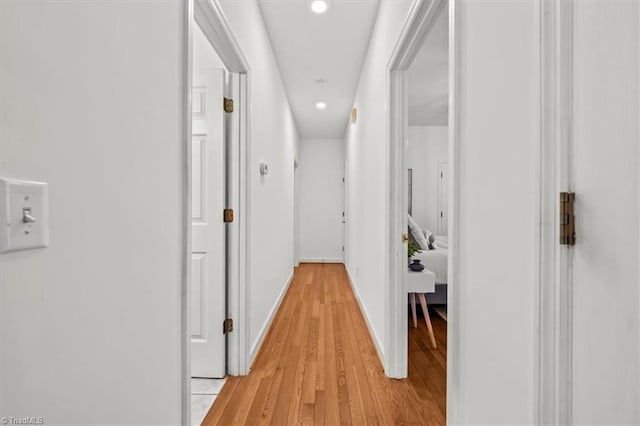 hall with baseboards, light wood finished floors, and recessed lighting
