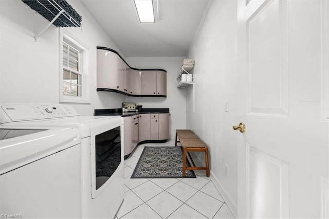 washroom with light tile patterned flooring, washer and clothes dryer, cabinet space, and baseboards