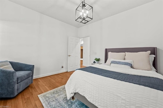 bedroom featuring hardwood / wood-style floors, baseboards, and a chandelier