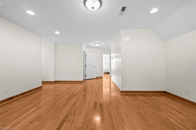 empty room with lofted ceiling, recessed lighting, baseboards, light wood finished floors, and visible vents