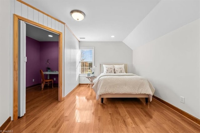 bedroom with baseboards, vaulted ceiling, and light wood-type flooring