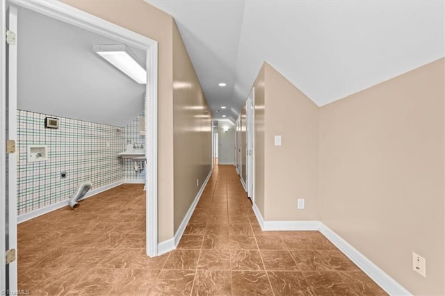 hall featuring baseboards, lofted ceiling, and recessed lighting