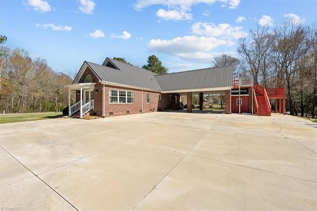 view of front of house featuring crawl space, metal roof, brick siding, and driveway