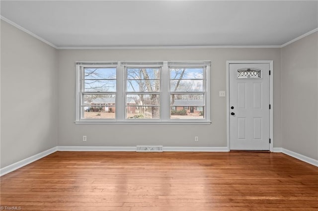 entryway featuring a wealth of natural light, ornamental molding, and light wood-type flooring