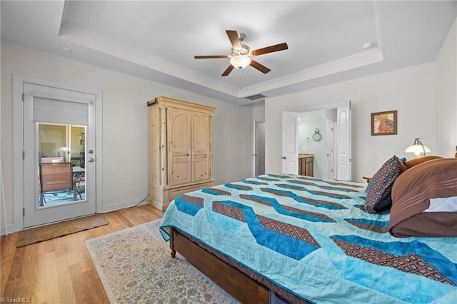 bedroom featuring light wood-type flooring, visible vents, ornamental molding, a raised ceiling, and ceiling fan