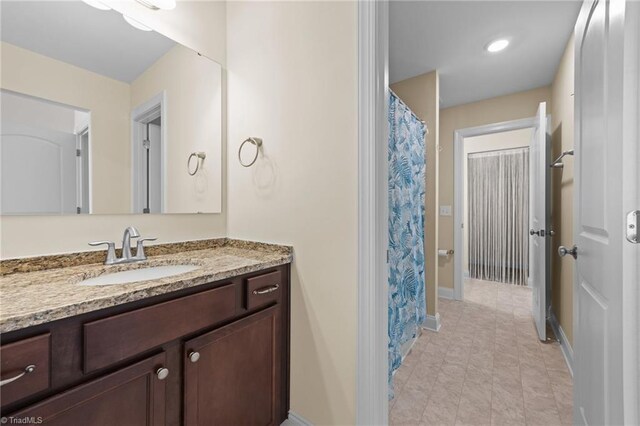 full bathroom with curtained shower, baseboards, and vanity