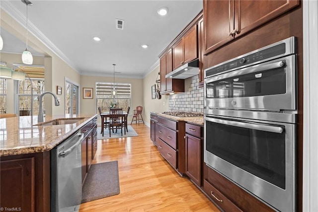 kitchen with visible vents, a sink, under cabinet range hood, tasteful backsplash, and stainless steel appliances