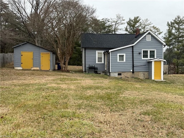 rear view of property with a lawn and a storage unit