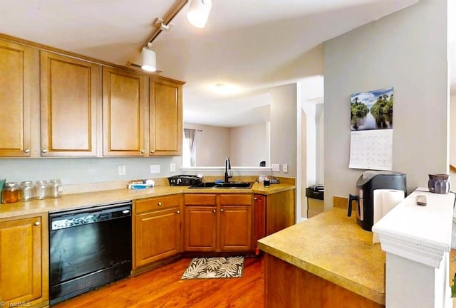 kitchen with brown cabinets, wood finished floors, a sink, light countertops, and black dishwasher