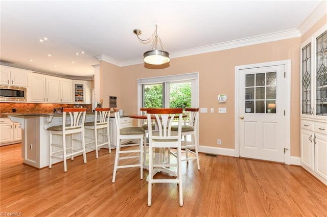 dining area featuring crown molding, light wood-type flooring, and baseboards