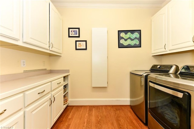 laundry area featuring baseboards, cabinet space, crown molding, washing machine and dryer, and light wood-type flooring