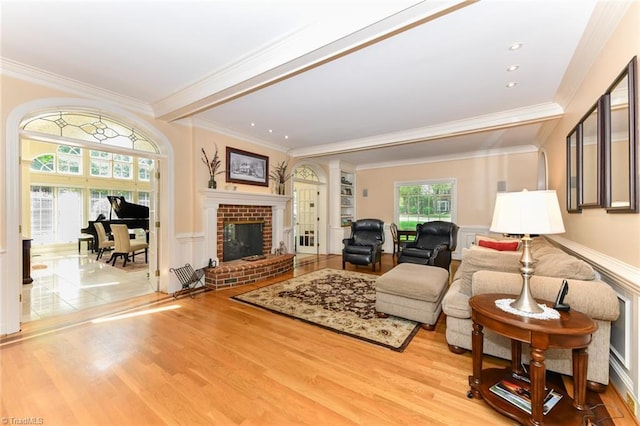 living area featuring a wainscoted wall, wood finished floors, a fireplace, and crown molding