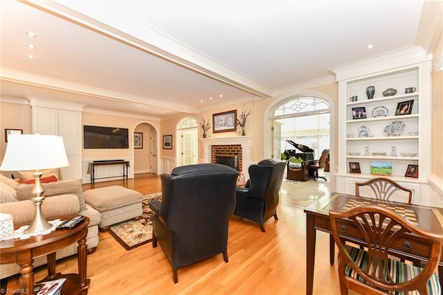 living area with arched walkways, light wood-style floors, a fireplace, and crown molding