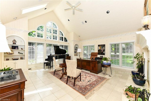 living area featuring built in shelves, a skylight, light tile patterned flooring, high vaulted ceiling, and a ceiling fan