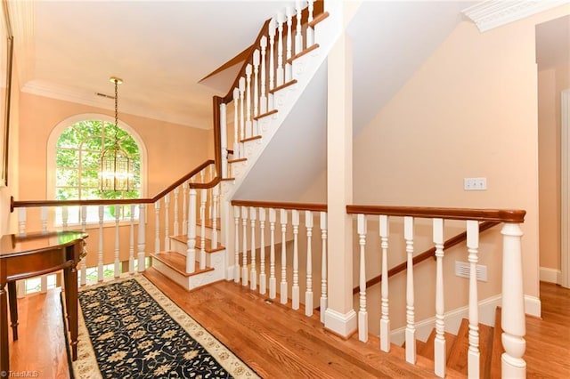 staircase featuring ornamental molding, baseboards, and wood finished floors