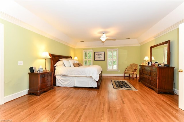 bedroom featuring ornamental molding, a ceiling fan, a tray ceiling, light wood-style floors, and baseboards