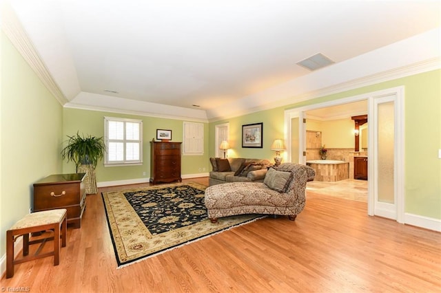 living area with visible vents, baseboards, light wood-style floors, and crown molding