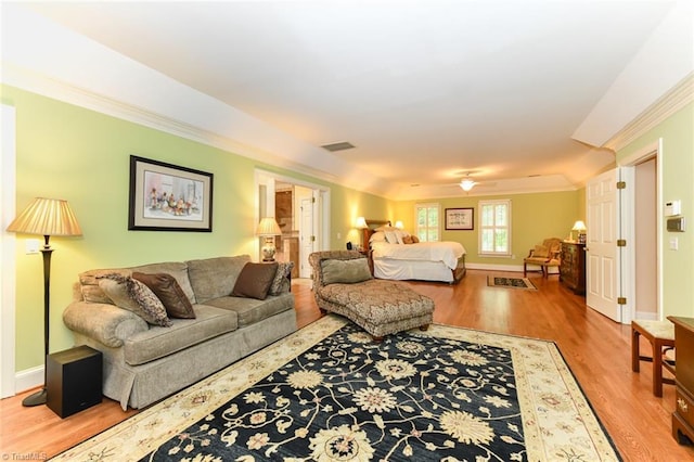 living room with a ceiling fan, wood finished floors, baseboards, visible vents, and crown molding