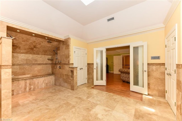 bathroom with french doors, tiled shower, and tile walls