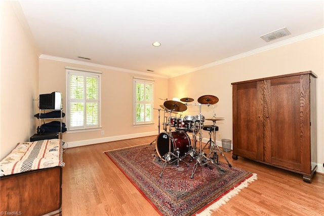 playroom featuring visible vents, light wood-style flooring, baseboards, and ornamental molding