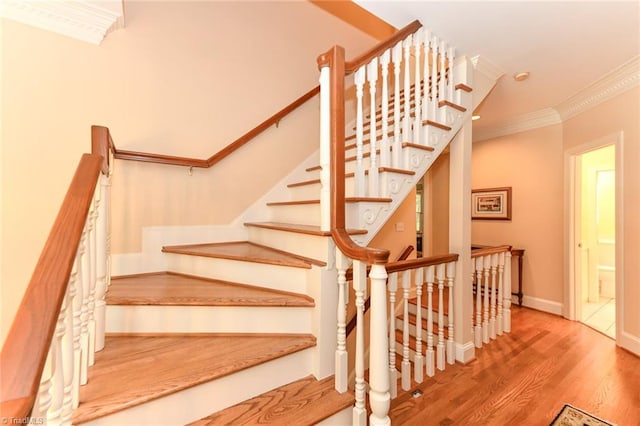 stairs featuring baseboards, wood finished floors, and ornamental molding