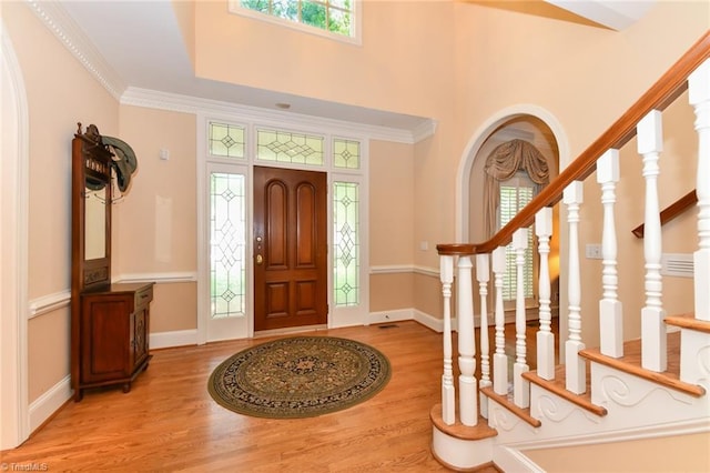 foyer featuring baseboards, wood finished floors, stairs, and ornamental molding