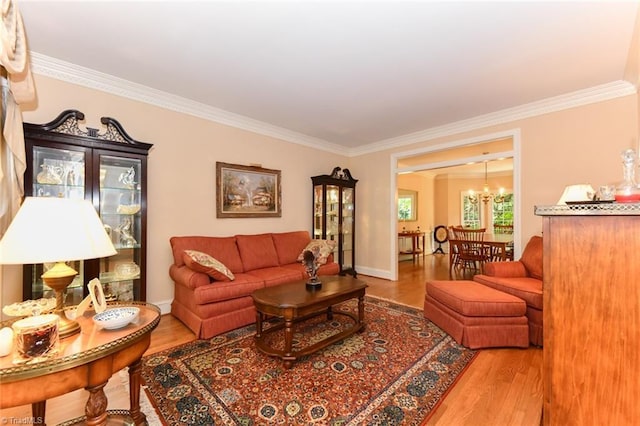 living room with crown molding, wood finished floors, baseboards, and a chandelier