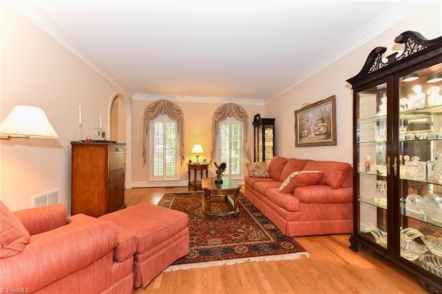 living room featuring wood finished floors, visible vents, and ornamental molding