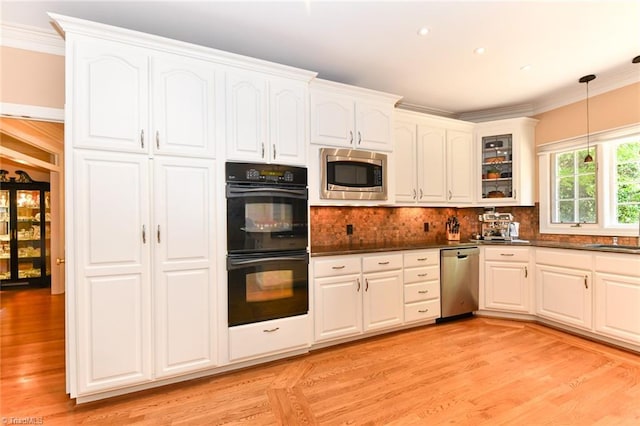 kitchen with dark countertops, appliances with stainless steel finishes, white cabinetry, and crown molding