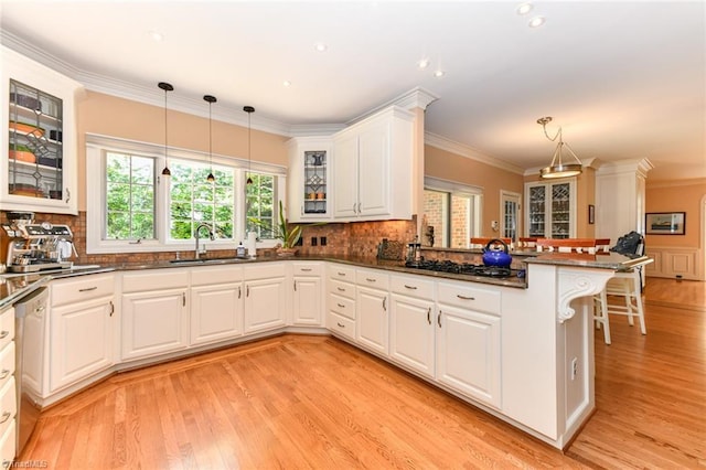 kitchen featuring ornamental molding, a peninsula, gas stovetop, and a sink