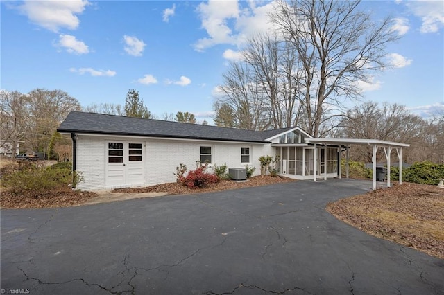 view of front facade featuring a carport, central AC unit, and a sunroom