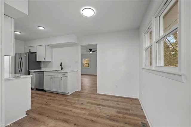 kitchen with white cabinetry, appliances with stainless steel finishes, light wood-type flooring, and decorative backsplash