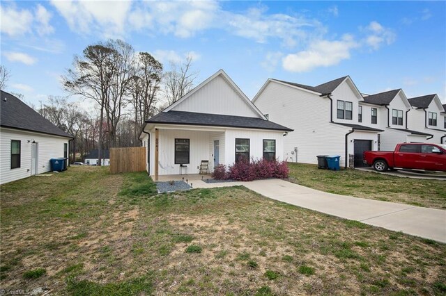modern farmhouse featuring a garage, a porch, a front yard, and fence