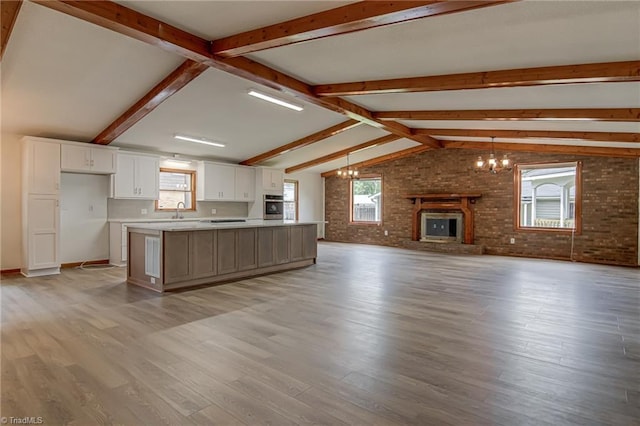 210 W Parkway Ave, High Point, NC 27284 - kitchen with oven, open floor plan, brick wall, white cabinets, and a chandelier