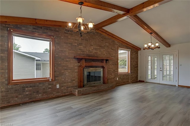 210 W Parkway Ave, High Point, NC 27284 - unfurnished living room with a chandelier, plenty of natural light, wood finished floors, and brick wall