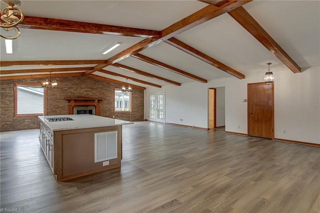 210 W Parkway Ave, High Point, NC 27284 - kitchen featuring a chandelier, open floor plan, wood finished floors, brick wall, and pendant lighting
