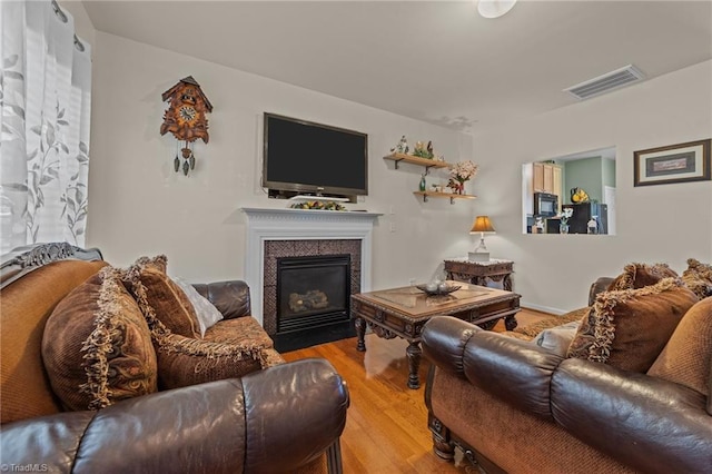 living room with visible vents, a fireplace with flush hearth, and wood finished floors