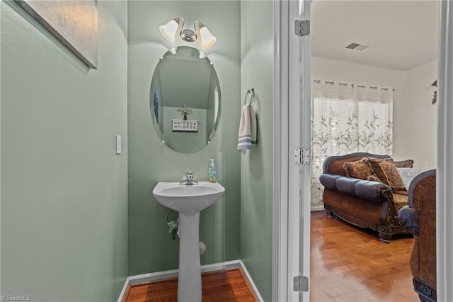 bathroom featuring baseboards, wood finished floors, and visible vents