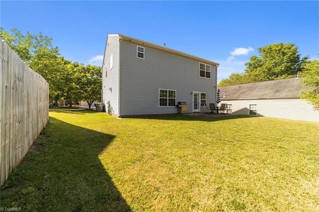 rear view of property featuring a lawn and fence