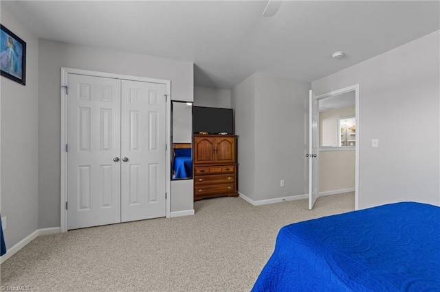 bedroom with baseboards, light colored carpet, ceiling fan, and a closet
