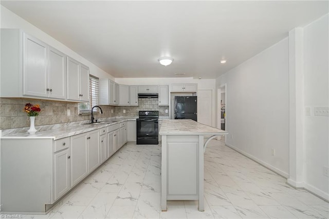 304 Ingram St, Thomasville, NC 27360 - kitchen featuring black appliances, light marble finish flooring, a kitchen island, backsplash, and under cabinet range hood