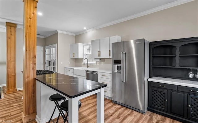 kitchen with open shelves, white cabinets, appliances with stainless steel finishes, crown molding, and light wood-type flooring