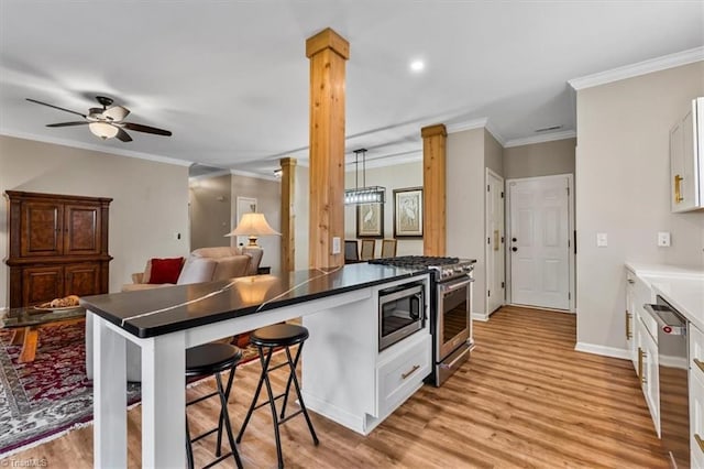 kitchen featuring a kitchen bar, appliances with stainless steel finishes, white cabinets, and light wood finished floors