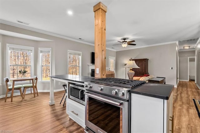 kitchen with dark countertops, visible vents, light wood-style flooring, appliances with stainless steel finishes, and white cabinetry